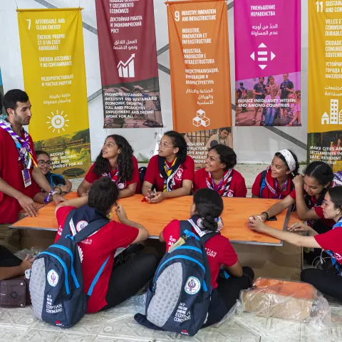Kids gathered around a leader to learn abouth the SDGs